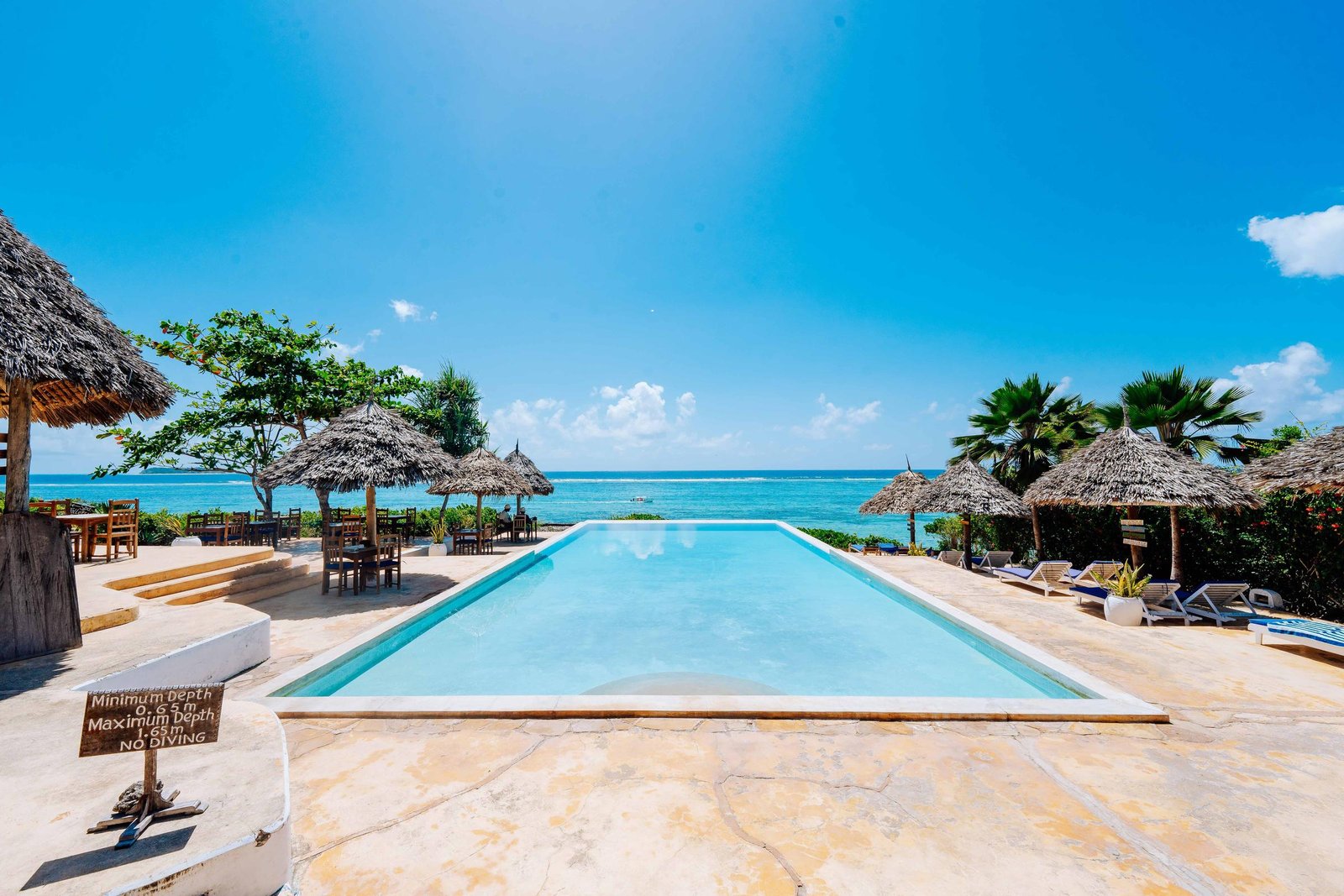Kasha's main swimming pool with thatched umbrellas and the turquoise sea of Matemwe beyond