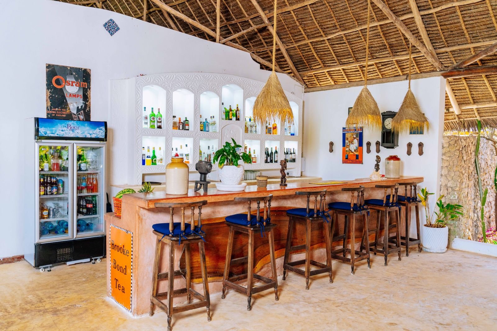 Kasha's bar with high stools, a thatched roof and shelves of spirits