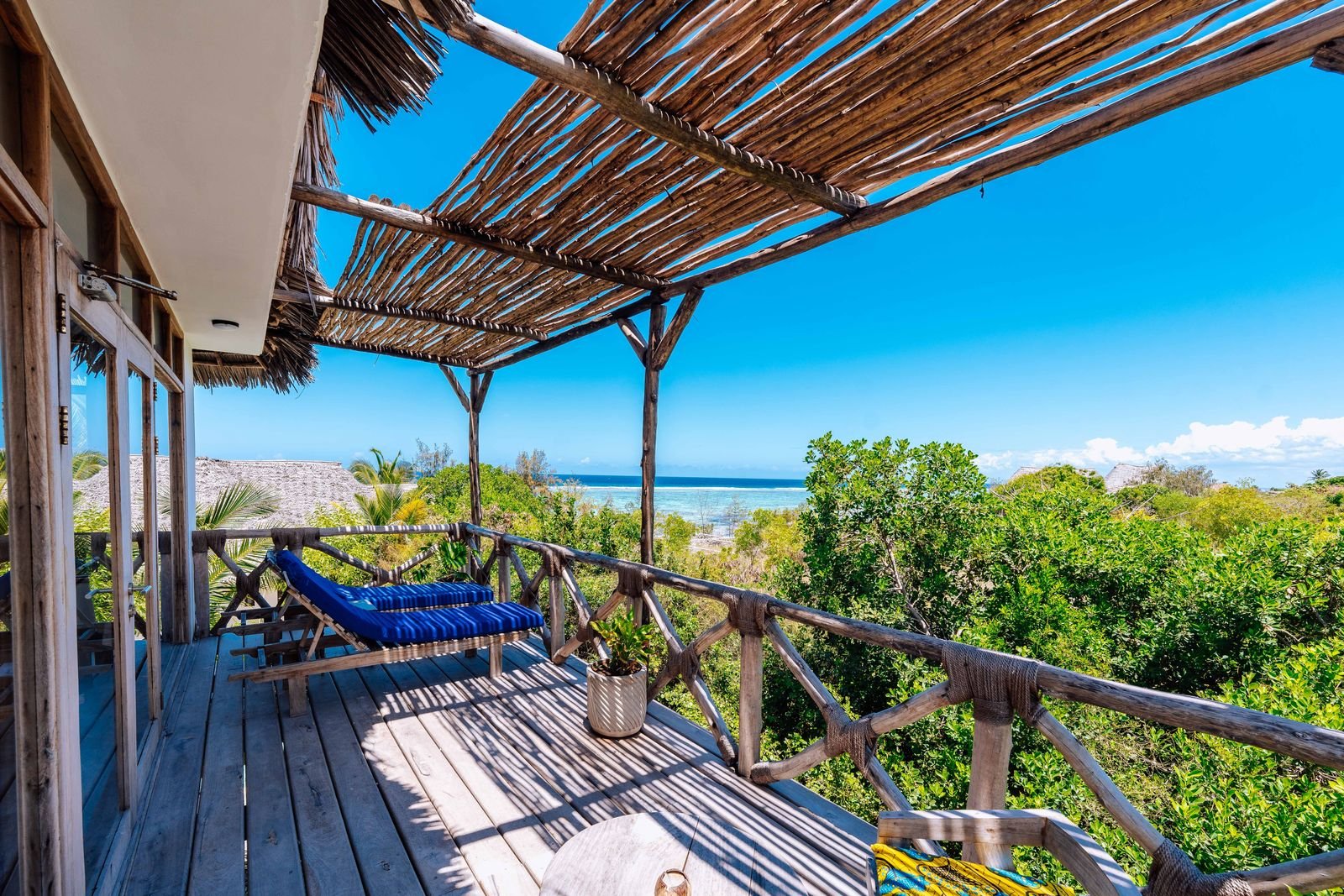 First floor balcony with a daybed and a panoramic view over the trees to the sea