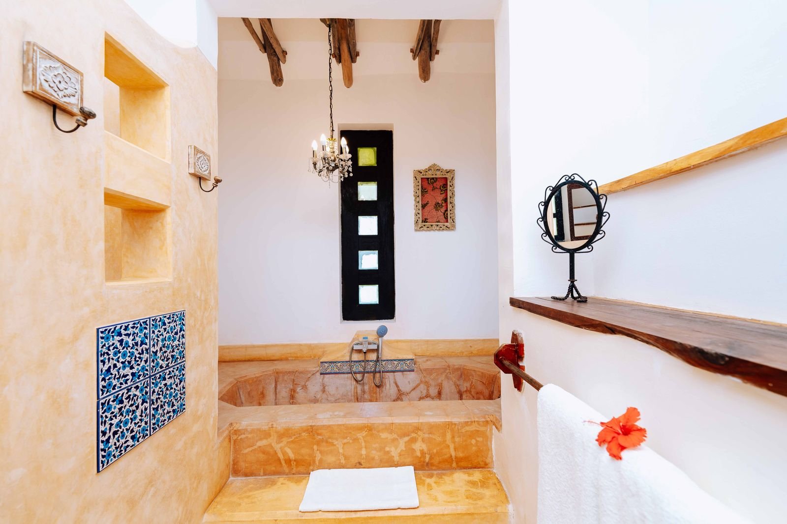 Swahili-style bathroom with a sunken stone bathtub and carved details