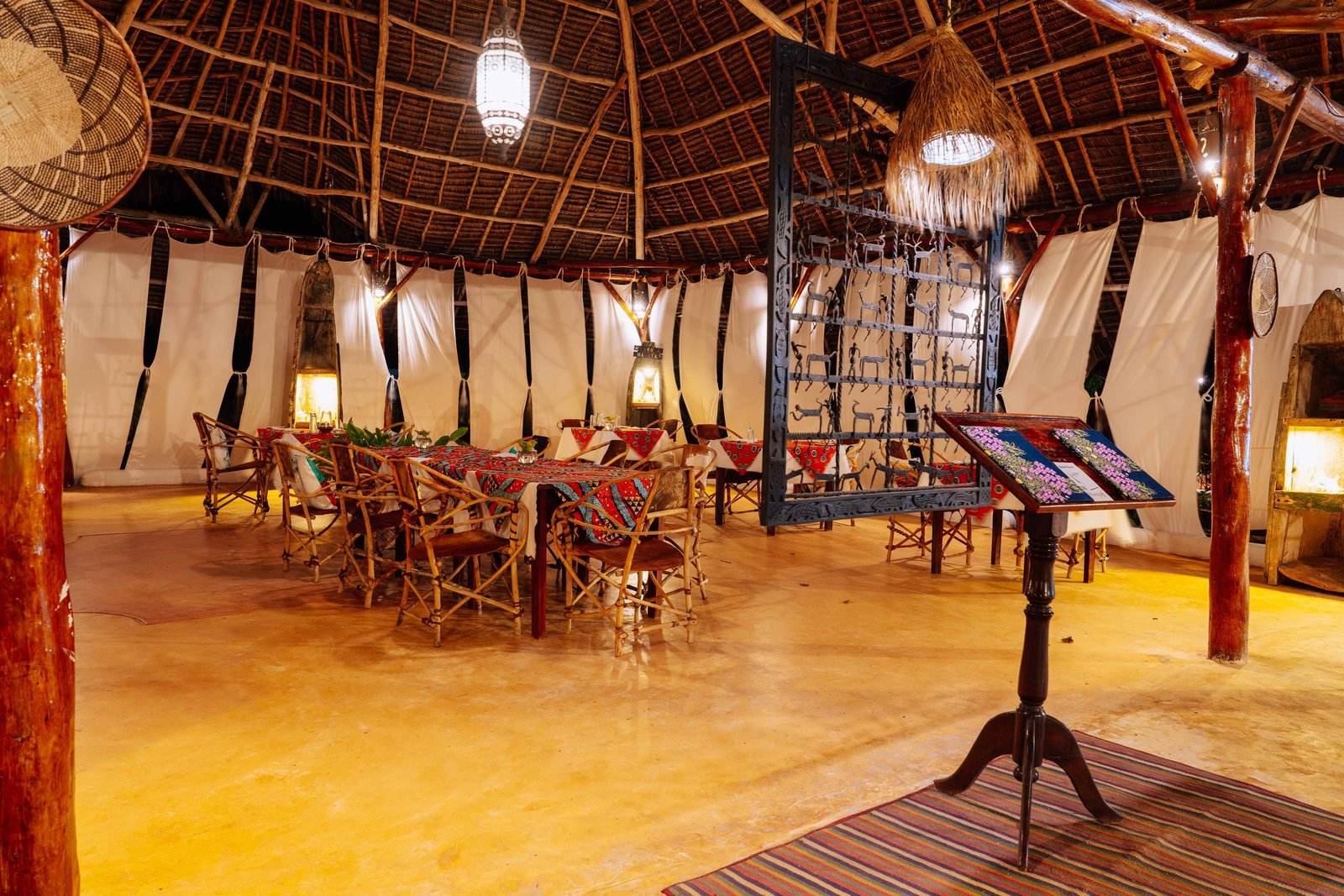 Sama Restaurant under a high thatched roof with tables set for dinner