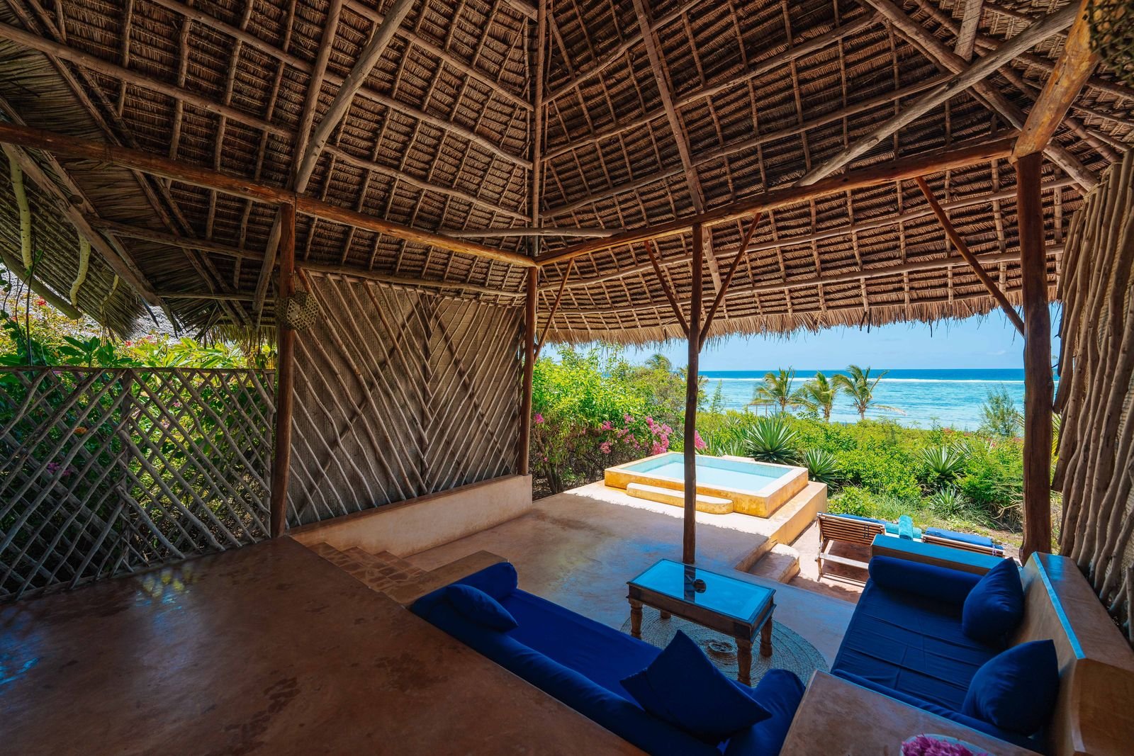Thatched Swahili-style villa terrace with blue sofas and a private plunge pool overlooking the ocean