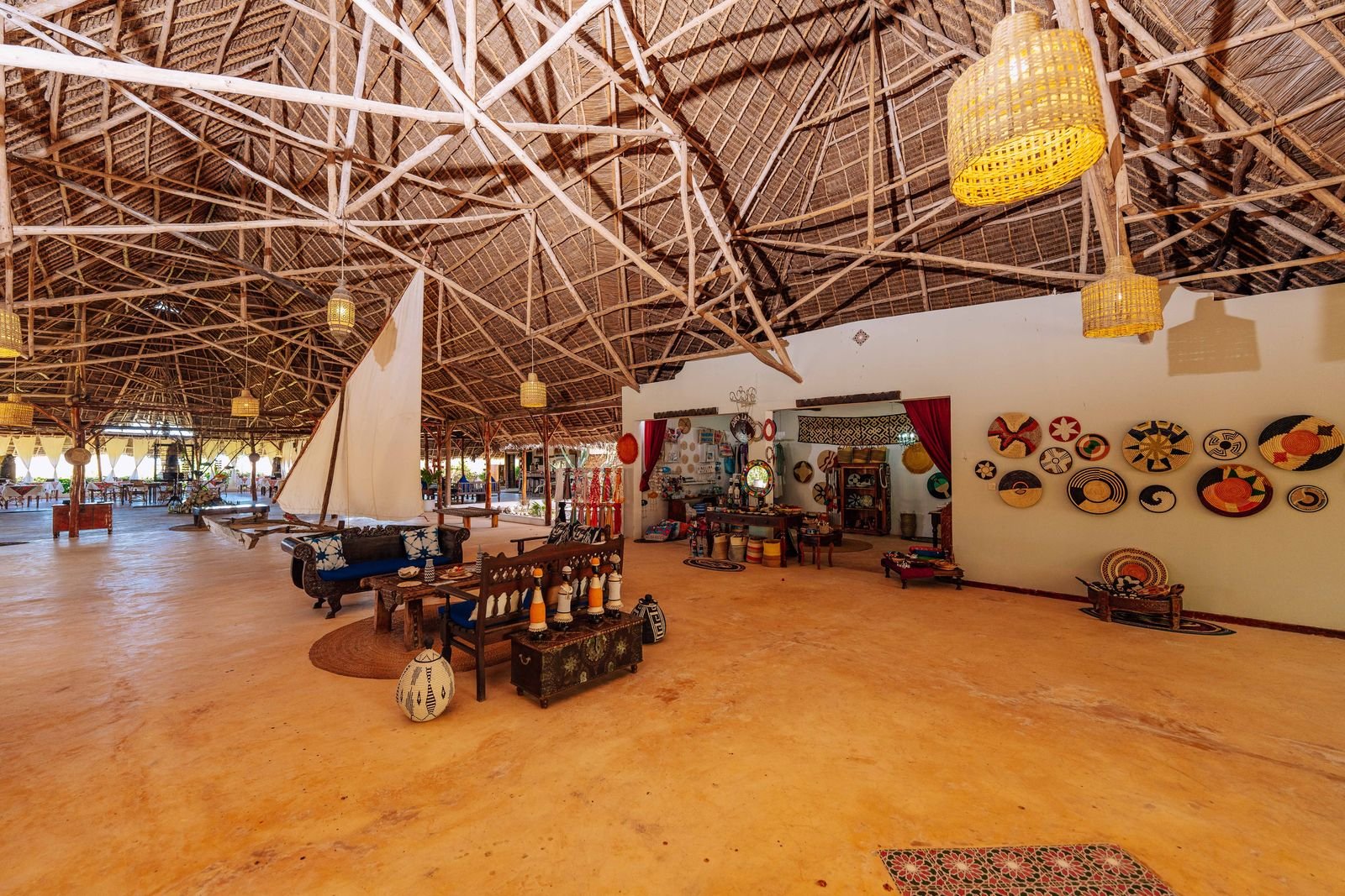 Kasha's open lounge under a high thatched roof, decorated with Zanzibari crafts and woven baskets