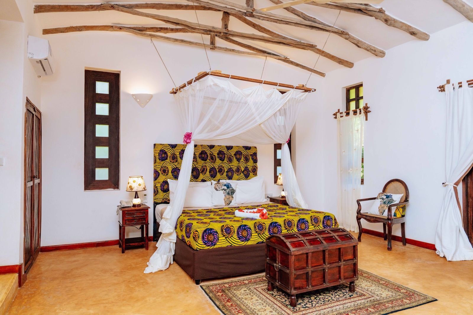 Sea Front Villa bedroom with a canopy bed, African print bedspread and Swahili wooden chest
